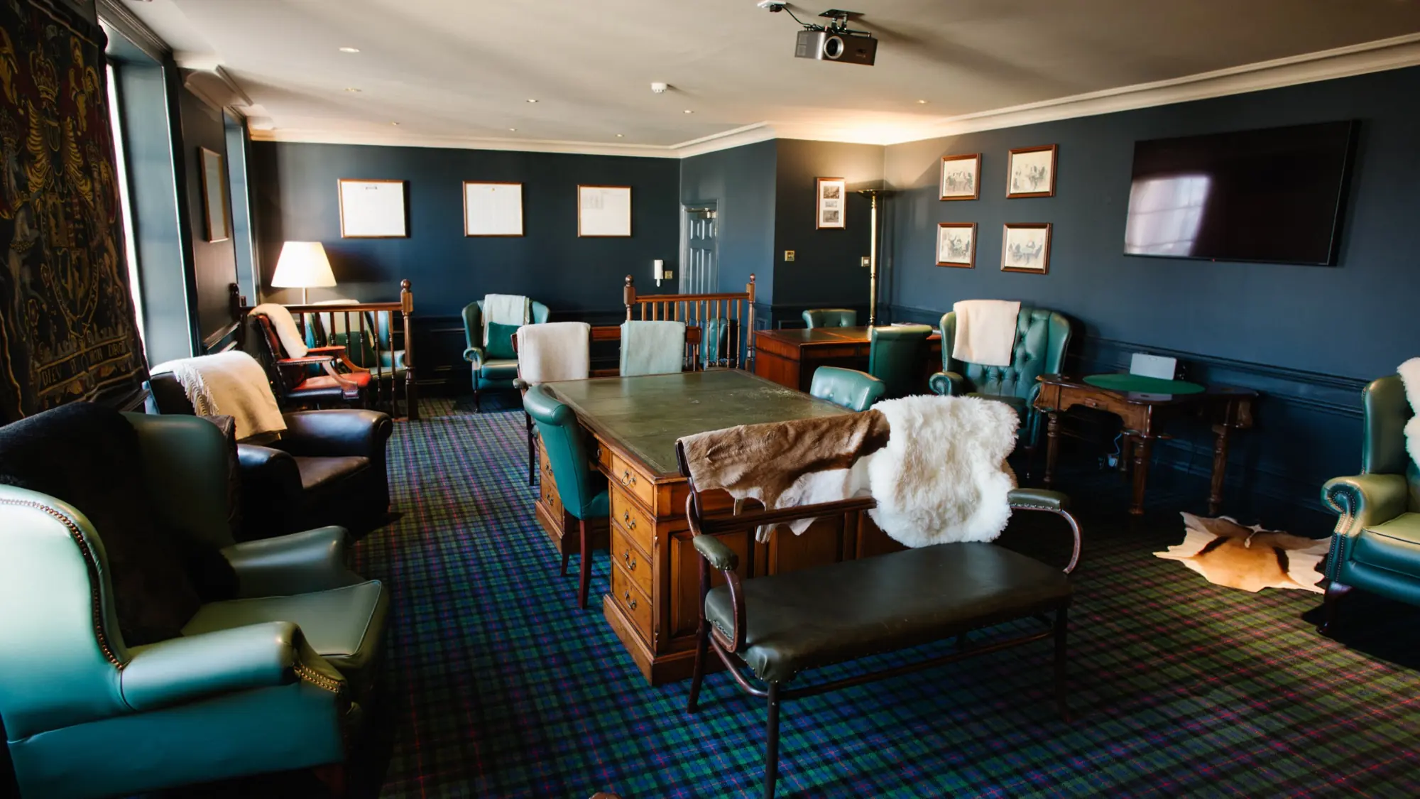 The Heavey Room: a partners’ desk, green leather chairs, tartan carpet and a large screen