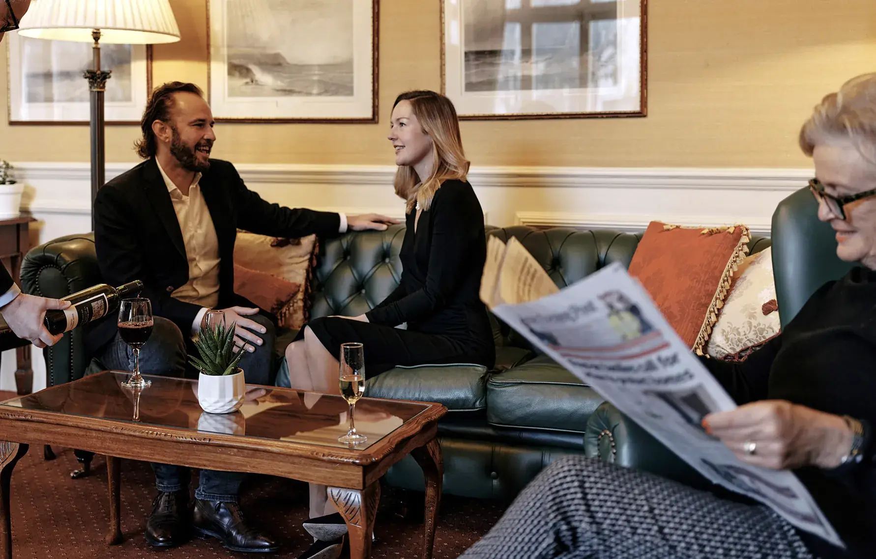 Members in conversation on the green leather sofas