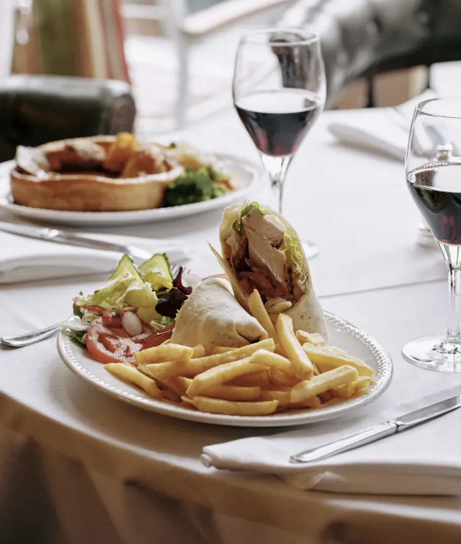 A chicken wrap with chips, a glass of red wine and a Yorkshire pudding lunch on white linen